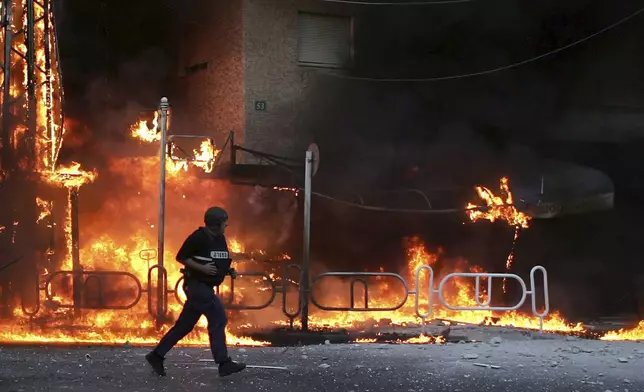 FILE - An Israeli police officer runs to the site where a Hezbollah-fired rocket directly hit a building in the northern costal town of Nahariya, on July 13, 2006. (AP Photo/Ariel Schalit, File)