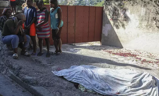 Residents gather before a person they say was killed in an attack by gang members, in the Pétion-Ville neighborhood of Port-au-Prince, Haiti, Tuesday, Nov. 19, 2024. (AP Photo/Odelyn Joseph)