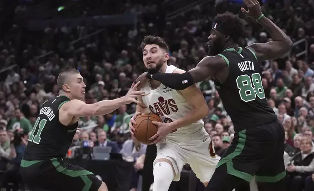 Cleveland Cavaliers guard Ty Jerome, center, tries to drive between Boston Celtics guard Payton Pritchard (11) and center Neemias Queta (88) during the first half of an Emirates NBA Cup basketball game, Tuesday, Nov. 19, 2024, in Boston. (AP Photo/Charles Krupa)