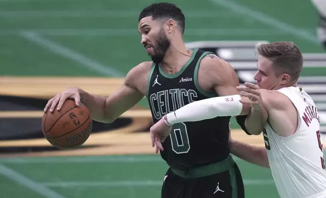 Boston Celtics forward Jayson Tatum (0) holds back Cleveland Cavaliers guard Sam Merrill (5) on a drive to the basket during the second half of an Emirates NBA Cup basketball game, Tuesday, Nov. 19, 2024, in Boston. (AP Photo/Charles Krupa)