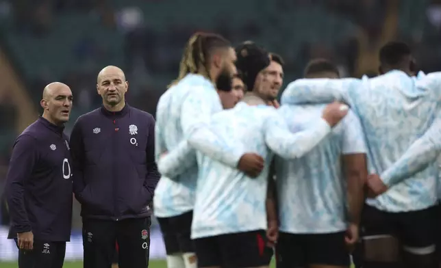 England's head coach Steve Borthwick, second from left, with a team staff member watch players huddle together ahead of the Autumn Nations series rugby union match between England and Australia, at Twickenham stadium, London Saturday, Nov. 9, 2024. (AP Photo/Ian Walton)