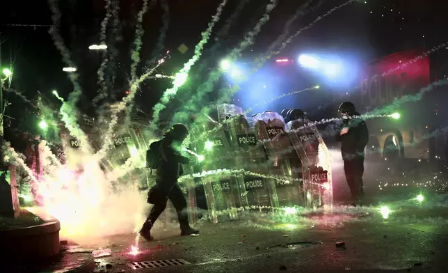 Demonstrators use firecrackers against police as police block a street to prevent protesters rallying against the government's decision to suspend negotiations on joining the European Union for four years, outside the parliament's building in Tbilisi, Georgia, early Saturday, Nov. 30, 2024. (AP Photo/Zurab Tsertsvadze)