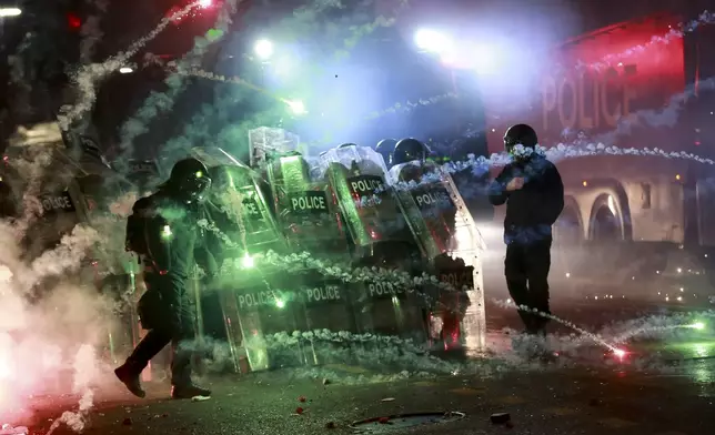 Demonstrators use firecrackers against police as police block a street to prevent protesters rallying against the government's decision to suspend negotiations on joining the European Union for four years, outside the parliament's building in Tbilisi, Georgia, early Saturday, Nov. 30, 2024. (AP Photo/Zurab Tsertsvadze)