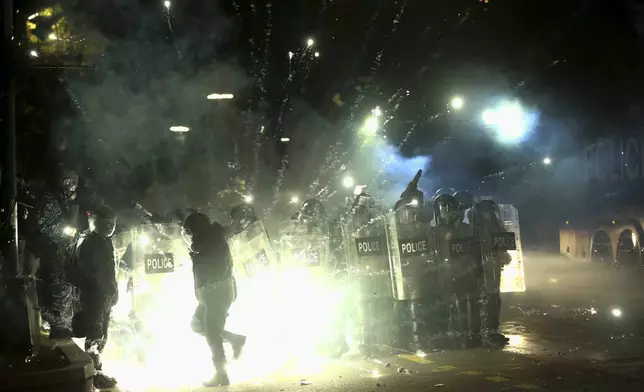 Demonstrators use firecrackers against police as police block a street to prevent protesters rallying against the government's decision to suspend negotiations on joining the European Union for four years, outside the parliament's building in Tbilisi, Georgia, early Saturday, Nov. 30, 2024. (AP Photo/Zurab Tsertsvadze)