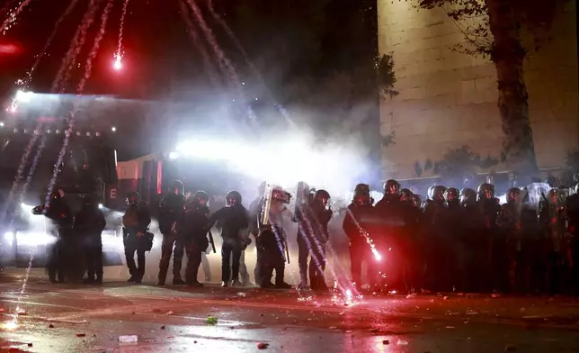 Demonstrators use firecrackers against police as police block a street to prevent protesters rallying against the government's decision to suspend negotiations on joining the European Union for four years, outside the parliament's building in Tbilisi, Georgia, early Saturday, Nov. 30, 2024. (AP Photo/Zurab Tsertsvadze)