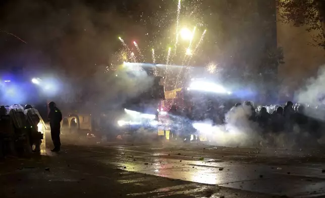 Demonstrators use firecrackers against police as police block a street to prevent protesters rallying against the government's decision to suspend negotiations on joining the European Union for four years, outside the parliament's building in Tbilisi, Georgia, early Saturday, Nov. 30, 2024. (AP Photo/Zurab Tsertsvadze)