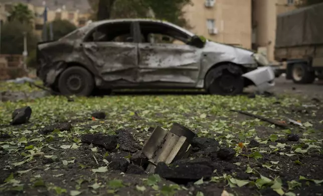 A rocket, fired from Lebanon during the night hours before the start of the ceasefire, sits wedged in the ground next to a damaged car in Kiryat Shmona, northern Israel, Wednesday, Nov. 27, 2024. (AP Photo/Leo Correa)