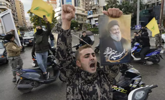 A man celebrates carrying a picture of slain Hezbollah leader Hassan Nasrallah in Dahiyeh, Beirut, Lebanon, following a ceasefire between Israel and Hezbollah that went into effect on Wednesday, Nov. 27, 2024. (AP Photo/Bilal Hussein)