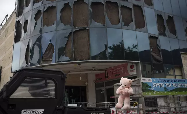 A worker drives his vehicle past a mall that was damaged following a rocket attack fired from Lebanon during the night, hours before the start of the ceasefire, in Kiryat Shmona, northern Israel, Wednesday, Nov. 27, 2024. (AP Photo/Leo Correa)