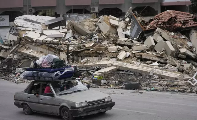 Displaced residents drive past the rubble of destroyed buildings as they return to their villages, following a ceasefire between Israel and Hezbollah that went into effect on Wednesday, Nov. 27, 2024, in Tyre, southern Lebanon. (AP Photo/Hussein Malla)