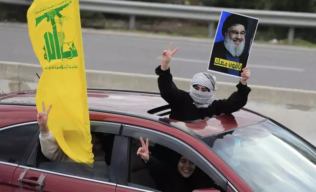 A woman carries a picture of slain Hezbollah leader Hassan Nasrallah as people celebrate a ceasefire between Israel and Hezbollah that went into effect on Wednesday, Nov. 27, 2024, in Ghazieh, Lebanon. (AP Photo/Mohammed Zaatari)