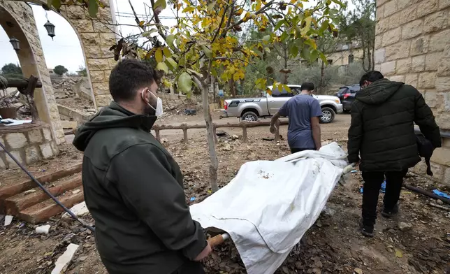 Lebanese men carry a dead body retrieved from under the rubble of a destroyed house in Ainata village, southern Lebanon, following a ceasefire between Israel and Hezbollah that went into effect on Wednesday, Nov. 27, 2024. (AP Photo/Hussein Malla)