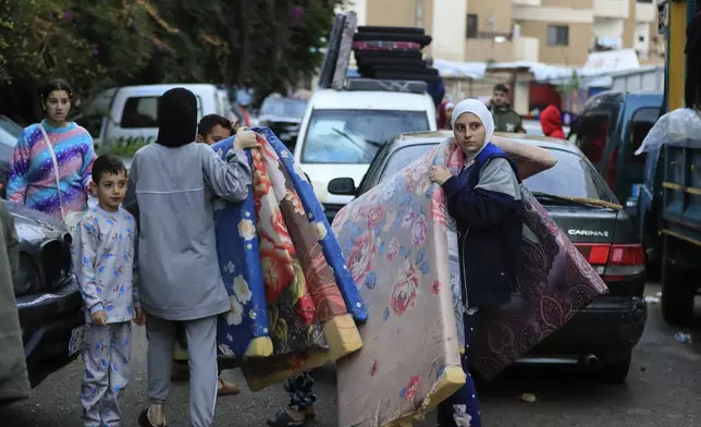 Displaced families carry mattresses as they prepare to return to their villages after a ceasefire between Israel and Hezbollah went into effect in Sidon, Lebanon, Wednesday, Nov. 27, 2024. (AP Photo/Mohammed Zaatari)