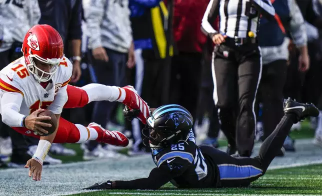 Kansas City Chiefs quarterback Patrick Mahomes (15) falls after a hit by Carolina Panthers safety Xavier Woods (25) during the first half of an NFL football game, Sunday, Nov. 24, 2024, in Charlotte, N.C. (AP Photo/Jacob Kupferman)