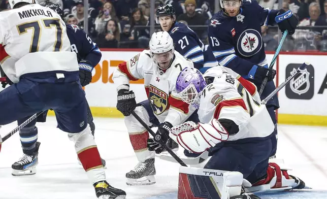 Florida Panthers goaltender Sergei Bobrovsky (72) saves the shot from Winnipeg Jets' Mark Scheifele (55) as Dmitry Kulikov (7) defends during the second period of an NHL hockey game in Winnipeg, Manitoba, Tuesday, Nov. 19, 2024. (Fred Greenslade/The Canadian Press via AP)