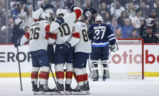 The Florida Panthers' Uvis Balinskis (26) and Nate Schmidt (88) celebrate A.J. Greer's (10) goal against the Winnipeg Jets during the second period of an NHL hockey game in Winnipeg, Manitoba, Tuesday, Nov. 19, 2024. (Fred Greenslade/The Canadian Press via AP)