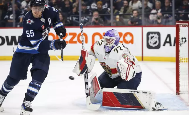 Winnipeg Jets' Mark Scheifele (55) attempts to deflect the puck past Florida Panthers' goaltender Sergei Bobrovsky (72) during the second period of an NHL hockey game in Winnipeg, Manitoba, Tuesday, Nov. 19, 2024. (Fred Greenslade/The Canadian Press via AP)