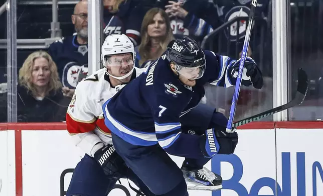 Florida Panthers' Dmitry Kulikov (7) trips Winnipeg Jets' Vladislav Namestnikov (7) during the second period of an NHL hockey game in Winnipeg, Manitoba, Tuesday, Nov. 19, 2024. (Fred Greenslade/The Canadian Press via AP)