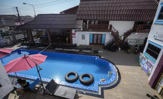 A foreign tourist rests near a swimming pool at Nana Backpackers hostel in Vang Vieng, Laos, Friday, Nov. 22, 2024. (AP Photo/Anupam Nath)