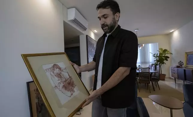 Lubnan Baalbaki shows a sketch depicting him while he was asleep drawn by his late father, during an interview with The Associated Press at his house in Geitawi, Beirut, Lebanon, Thursday, Oct. 31, 2024. (AP Photo/Bilal Hussein)