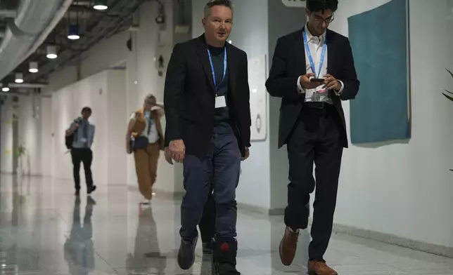 Australia Climate Minister Chris Bowen, center, walks through a hallway at the COP29 U.N. Climate Summit in the early hours of Saturday, Nov. 23, 2024, in Baku, Azerbaijan. (AP Photo/Joshua A. Bickel)