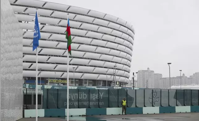 A member of security stands with the Baku Olympic Stadium in the background during the COP29 U.N. Climate Summit, Saturday, Nov. 23, 2024, in Baku, Azerbaijan. (AP Photo/Sergei Grits)