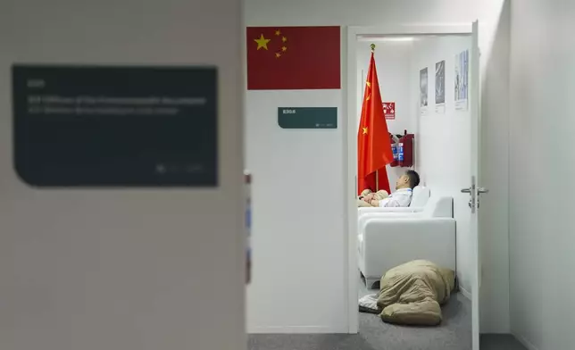 People sleep in the Chinese delegation offices at the COP29 U.N. Climate Summit in the early hours of Saturday, Nov. 23, 2024, in Baku, Azerbaijan. (AP Photo/Joshua A. Bickel)