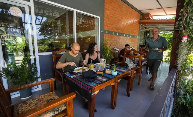 Neil Farmiloe, a New Zealander who owns the Kiwi Kitchen restaurant, serves food to the foreign tourist in Vang Vieng, Laos, Friday, Nov. 22, 2024. (AP Photo/Anupam Nath)