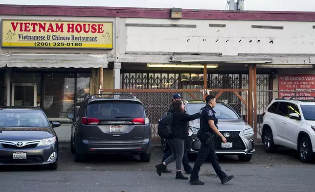 Police officers gather security camera footage from nearby businesses after multiple people were stabbed earlier in the area Friday, Nov. 8, 2024, in the Chinatown-International District in Seattle. (AP Photo/Lindsey Wasson)