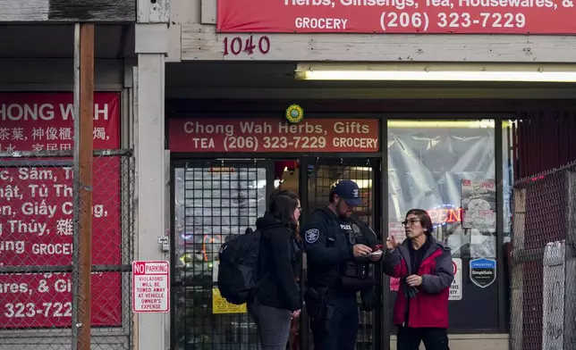 Police officers take a statement from a nearby business owner after multiple people were stabbed Friday, Nov. 8, 2024, in the Chinatown-International District in Seattle. (AP Photo/Lindsey Wasson)