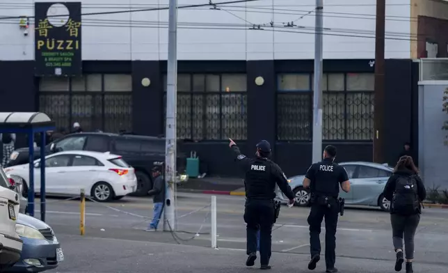 Police officers stand near the scene as they gather security camera footage after multiple people were stabbed in the area Friday, Nov. 8, 2024, in the Chinatown-International District in Seattle. (AP Photo/Lindsey Wasson)