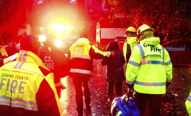 Firefighters help a woman from a home after a tree toppled onto it during heavy rains on Wednesday, Nov. 20, 2024, in the Forest Hills community of unincorporated Sonoma County, Calif. (AP Photo/Noah Berger)