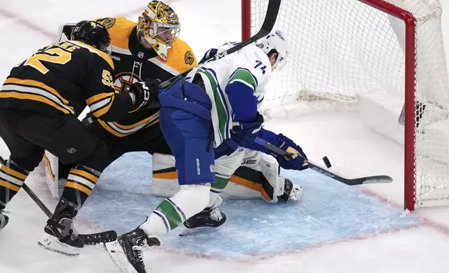 Vancouver Canucks left wing Jake DeBrusk (74) backhands a shot for a goal against Boston Bruins goaltender Jeremy Swayman (1) during the second period of an NHL hockey game, Tuesday, Nov. 26, 2024, in Boston. (AP Photo/Charles Krupa)