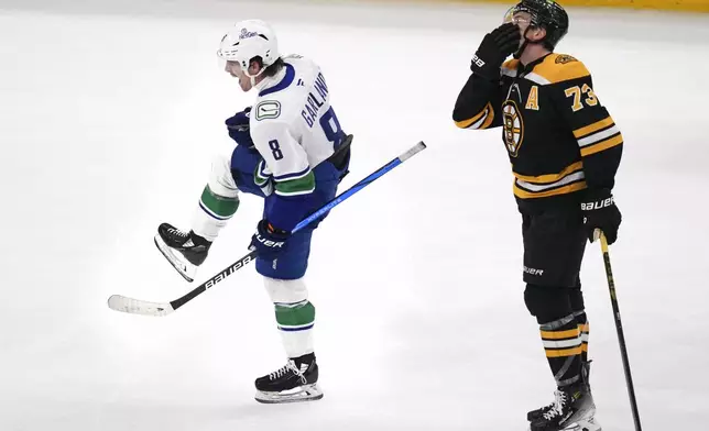 Vancouver Canucks right wing Conor Garland (8) celebrates while skating past Boston Bruins defenseman Charlie McAvoy (73) after scoring an empty net goal during the third period of an NHL hockey game, Tuesday, Nov. 26, 2024, in Boston. (AP Photo/Charles Krupa)