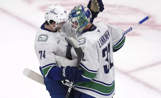 Vancouver Canucks goaltender Kevin Lankinen (32) is congratulated by Jake DeBrusk after shutting out the Boston Bruins 2-0 after an NHL hockey game, Tuesday, Nov. 26, 2024, in Boston. (AP Photo/Charles Krupa)