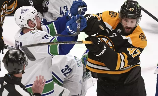 Boston Bruins center Mark Kastelic (47) and Vancouver Canucks defenseman Filip Hronek, left, battle during the second period of an NHL hockey game, Tuesday, Nov. 26, 2024, in Boston. (AP Photo/Charles Krupa)