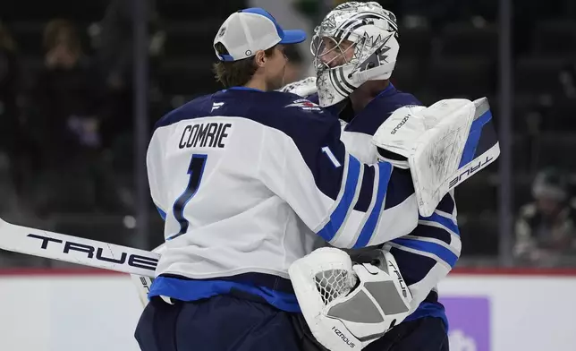 Winnipeg Jets goaltenders Connor Hellebuyck, right, and Eric Comrie (1) hug after their win over the Minnesota Wild in an NHL hockey game, Monday, Nov. 25, 2024, in St. Paul, Minn. (AP Photo/Abbie Parr)