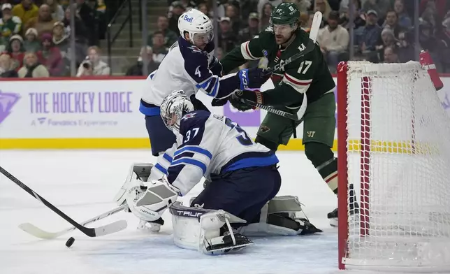 Winnipeg Jets goaltender Connor Hellebuyck (37) stops a shot during the first period of an NHL hockey game against the Minnesota Wild, Monday, Nov. 25, 2024, in St. Paul, Minn. (AP Photo/Abbie Parr)