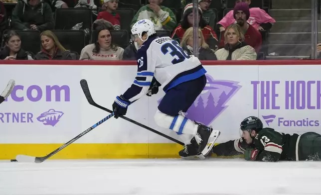 Winnipeg Jets center Morgan Barron (36) skates with the puck as Minnesota Wild center Marco Rossi (23) challenges during the third period of an NHL hockey game, Monday, Nov. 25, 2024, in St. Paul, Minn. (AP Photo/Abbie Parr)