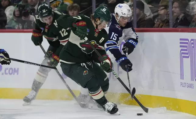 Minnesota Wild left wing Kirill Kaprizov (97), center, and Winnipeg Jets center Rasmus Kupari (15) fight for the puck during the first period of an NHL hockey game, Monday, Nov. 25, 2024, in St. Paul, Minn. (AP Photo/Abbie Parr)