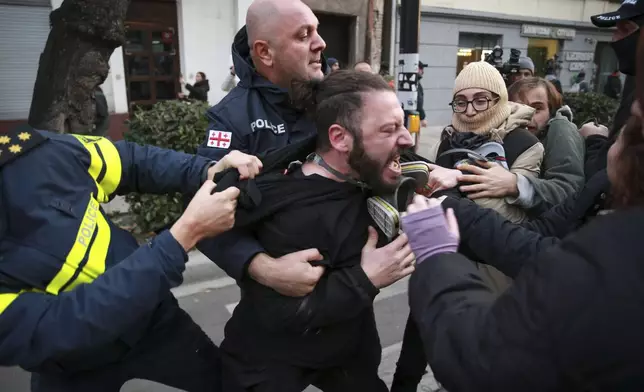 Police try to detain a protester in a street during a rally against the results of the parliamentary elections amid allegations that the vote was rigged in Tbilisi, Georgia, Tuesday, Nov. 19, 2024. (AP Photo/Zurab Tsertsvadze)