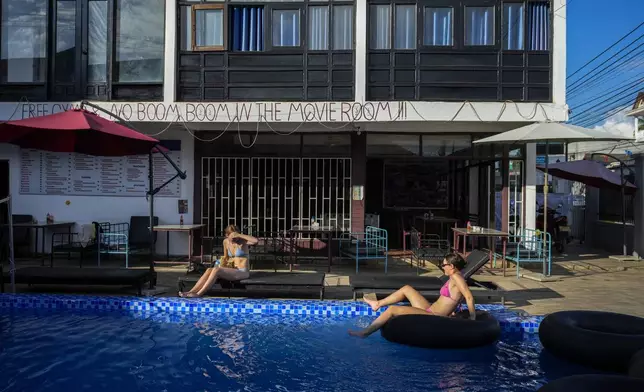 Foreign tourists relax at a swimming pool at Nana Backpack hostel in Vang Vieng, Laos, Tuesday, Nov. 19, 2024. (AP Photo/Anupam Nath)