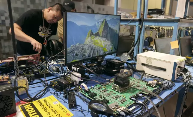 Employees work behind an evaluation board, foreground, in a lab at the d-Matrix office in Santa Clara, Calif., Wednesday, Oct. 16, 2024. (AP Photo/Jeff Chiu)