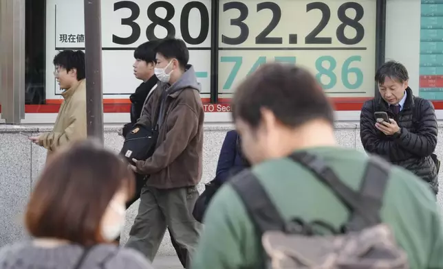 People walk in front of an electronic stock board showing Japan's Nikkei index at a securities firm Tuesday, Nov. 26, 2024, in Tokyo. (AP Photo/Eugene Hoshiko)