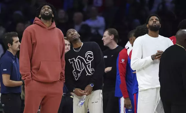 Philadelphia 76ers' Joel Embiid, from left, Tyrese Maxey and Paul George look towards the scoreboard during a timeout during the first half of an NBA basketball game against the Cleveland Cavaliers, Wednesday, Nov. 13, 2024, in Philadelphia. (AP Photo/Matt Slocum)