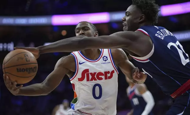 Philadelphia 76ers' Tyrese Maxey (0) and Los Angeles Clippers' Kobe Brown (21) reach for a loose ball during the second half of an NBA basketball game, Sunday, Nov. 24, 2024, in Philadelphia. (AP Photo/Matt Slocum)