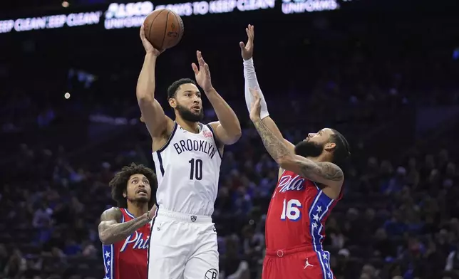 Brooklyn Nets' Ben Simmons, center, goes up for a shot between Philadelphia 76ers' Caleb Martin, right, and Kelly Oubre Jr. during the first half of an Emirates NBA Cup basketball game, Friday, Nov. 22, 2024, in Philadelphia. (AP Photo/Matt Slocum)