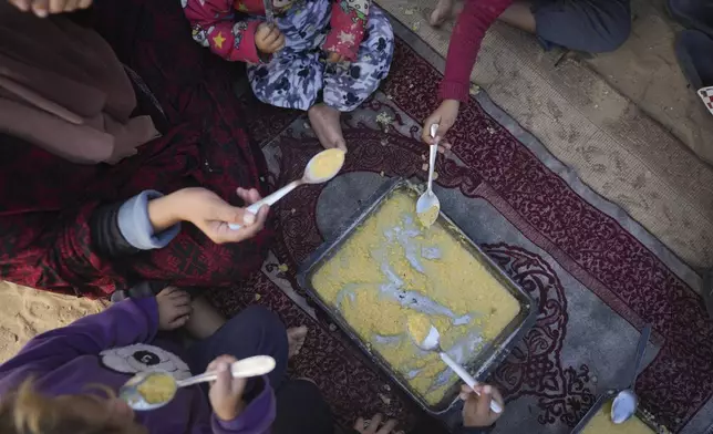 Yasmin Eid and her four daughters eat lentils at their tent in a refugee camp in Deir al-Balah, Gaza Strip, Tuesday, Nov. 19, 2024. (AP Photo/Abdel Kareem Hana)