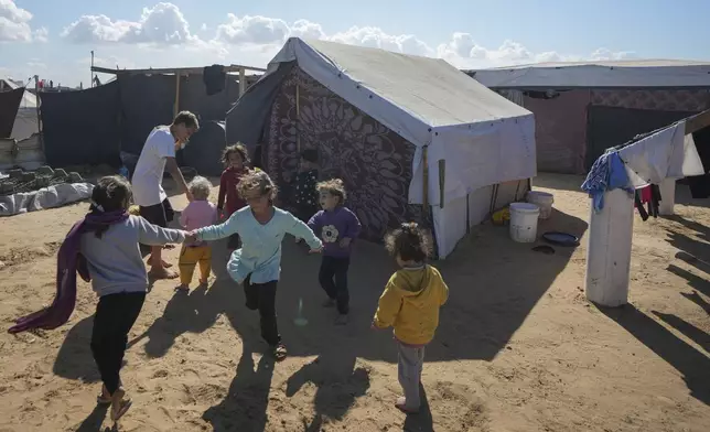 Children play next to their tent in a refugee camp in Deir al-Balah, Gaza Strip, Tuesday Nov. 19, 2024. (AP Photo/Abdel Kareem Hana)