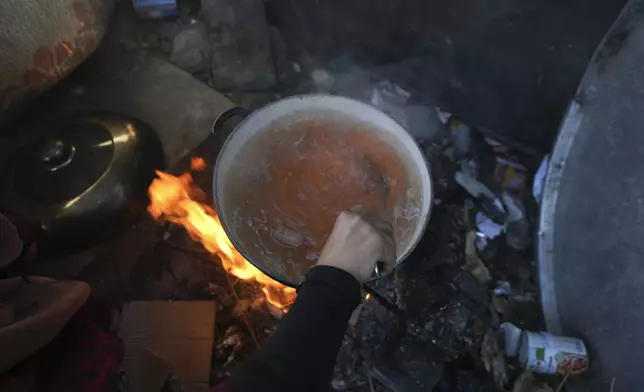 Yasmin Eid cooks a pot of lentils for her four daughters at their tent in a refugee camp in Deir al-Balah, Gaza Strip, Tuesday Nov. 19, 2024. (AP Photo/Abdel Kareem Hana)